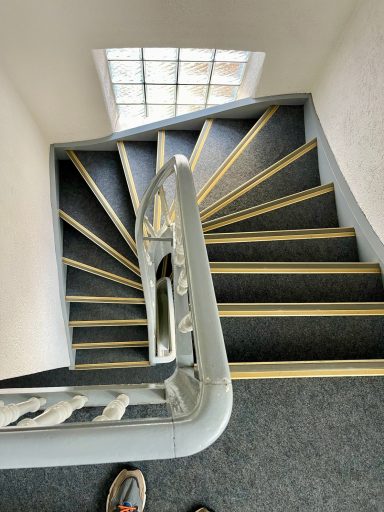 Eine Wendeltreppe mit grauem Boden und gelben Stufenmarkierungen.
