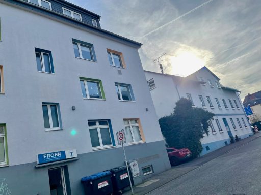 Zweistöckiges Wohnhaus mit Fenstern in verschiedenen Farben und sonnigem Himmel.
