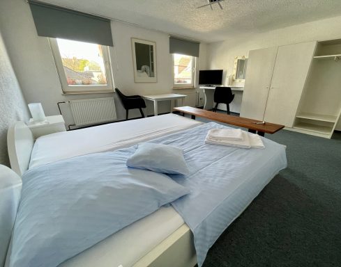 Ein helles Schlafzimmer mit einem Bett, Schreibtisch und TV. Ordnungsgemäße Einrichtung.