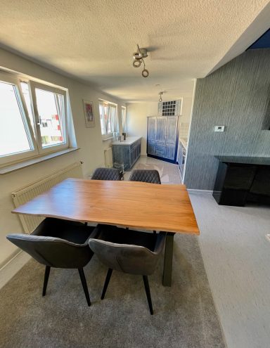 Modern Essbereich mit Holzttisch, Stühlen und großzügigen Fenstern.