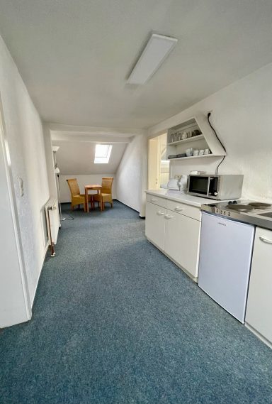 Küche mit Essbereich, helle Wände und Teppichboden im Raum.