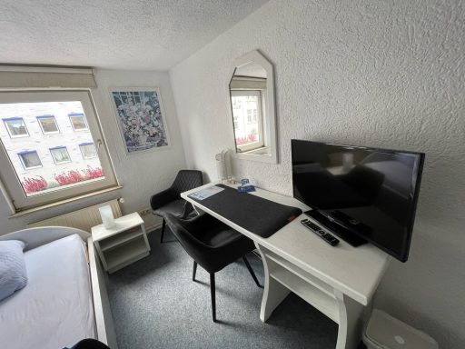 Modernes Hotelzimmer mit Schreibtisch, Stuhl, Fernseher und Fenster mit Ausblick.